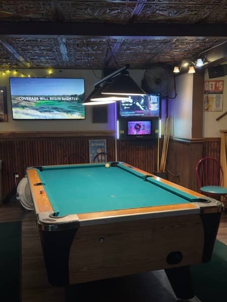 Pool table in Duffy's game room, with TVs and a jukebox in the background